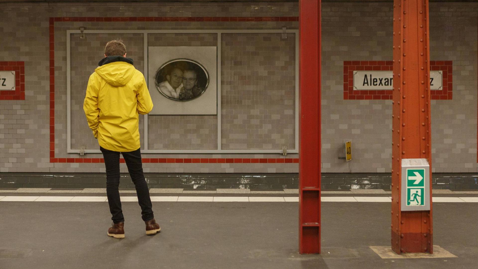 Ein Fahrgast in gelber Jacke steht alleine auf dem verlassenen Bahnsteig. Er steht mit dem Rücken zur Kamera und wartet auf einen Zug. Ein Fahrgast in gelber Jacke steht alleine auf dem verlassenen Bahnsteig. Er steht mit dem Rücken zur Kamera und wartet auf einen Zug.