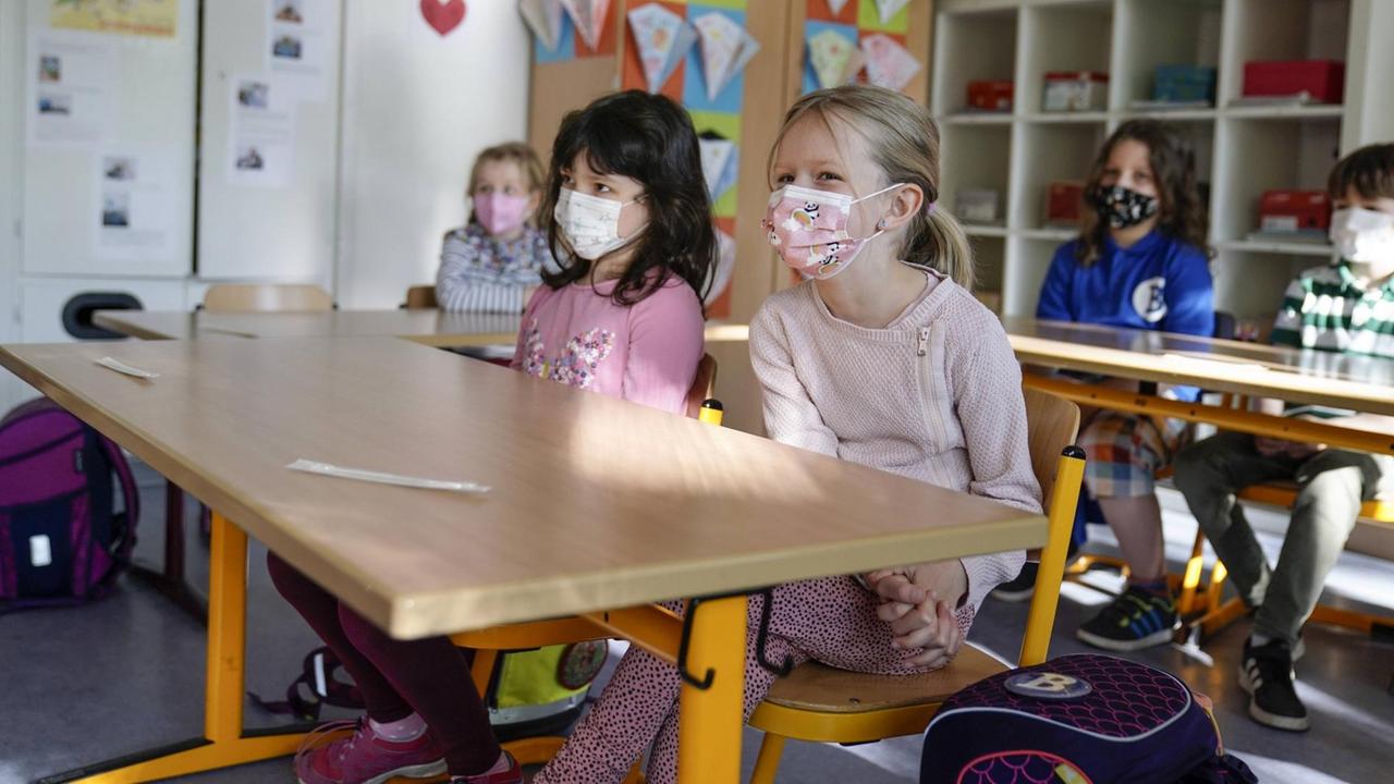Grundschülerinnen sitzen mit Mund-Nasen-Schutz in einem Klassenraum in Düsseldorf, vor ihnen liegen die Corona-Teststäbchen für den sogenannten Lolli-Test Grundschülerinnen sitzen mit Mund-Nasen-Schutz in einem Klassenraum in Düsseldorf, vor ihnen liegen die Corona-Teststäbchen für den sogenannten Lolli-Test