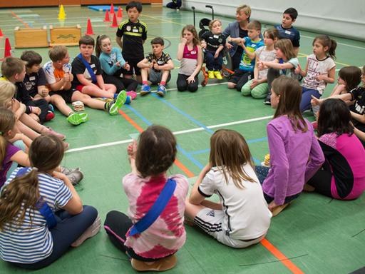 Die niedersächsische Kultusministerin Frauke Heiligenstadt (SPD, Hintergrund Mitte) sitzt am 27.04.2016 in der Sporthalle der Schule IGS Roderbruch in Hannover (Niedersachsen) während einer inklusiven Sportstunde mit Schülern in einem Kreis.