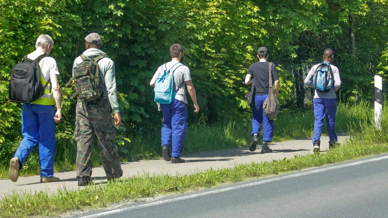 Leiharbeiter gehen an einer Straße entlang nach Feierabend Leiharbeiter gehen an einer Straße entlang nach Feierabend