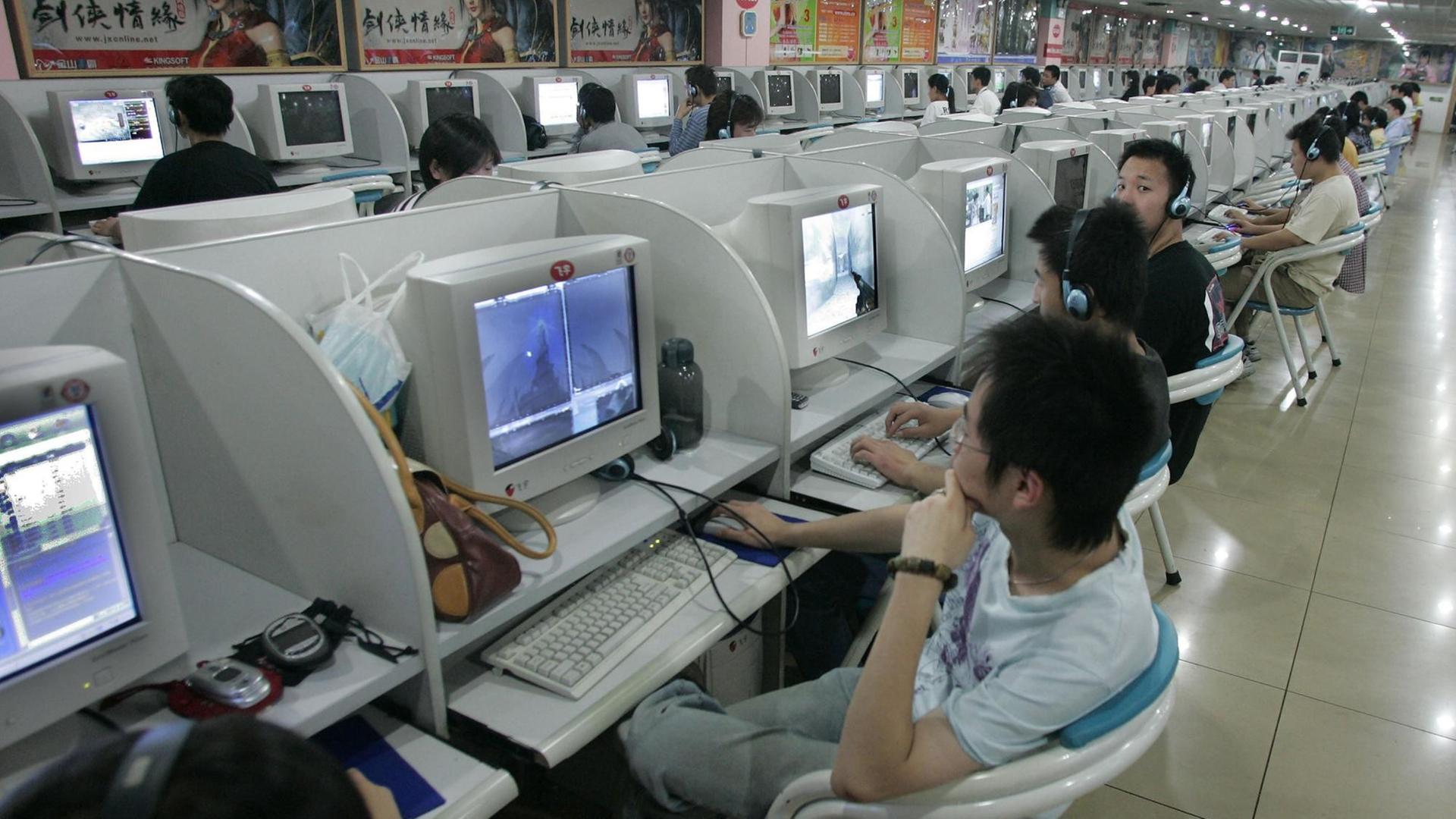 Blick in ein chinesisches Internetcafé: In einer Halle sind in langen Reihen Plätze mit Computern aufgebaut. Junge Menschen sitzen an den Rechnern. Blick in ein chinesisches Internetcafé: In einer Halle sind in langen Reihen Plätze mit Computern aufgebaut. Junge Menschen sitzen an den Rechnern.
