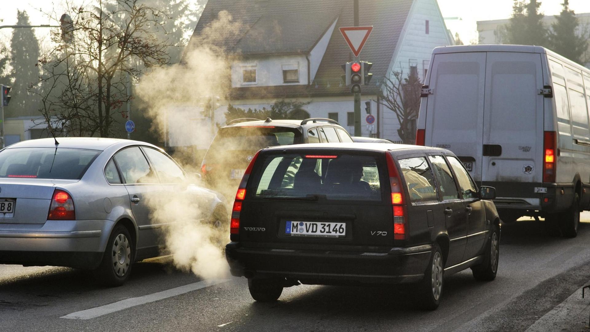 Autos, die Abgase aufstoßen, auf einer Straße in München Autos, die Abgase aufstoßen, auf einer Straße in München