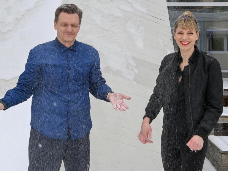 Thomas Oberender, Intendant der Berliner Festspiele, und Yvonne Büdenhölzer, Leiterin des Theatertreffens, stehen im Schnee vor dem Haus der Kulturen der Welt.