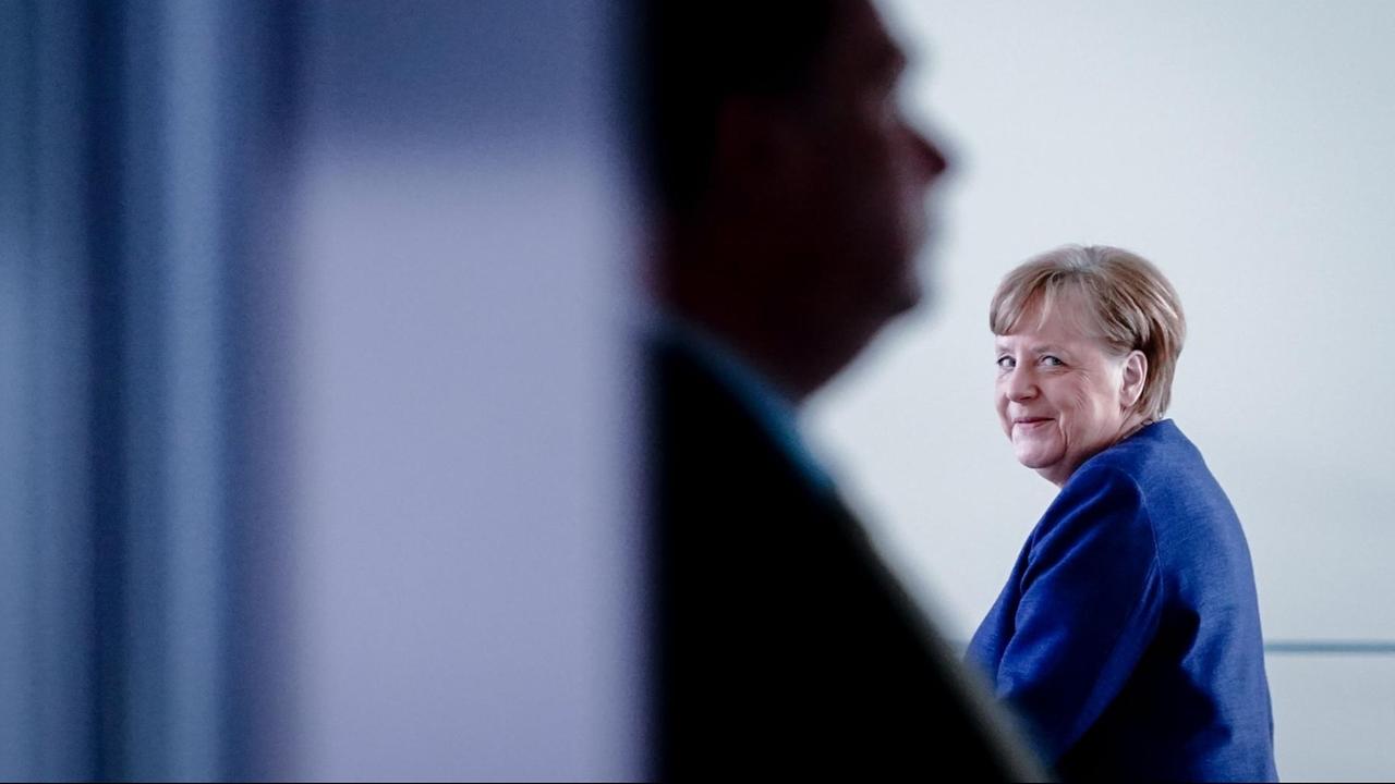 Bundeskanzlerin Angela Merkel geht grinsend um eine Ecke. Bundeskanzlerin Angela Merkel geht grinsend um eine Ecke.