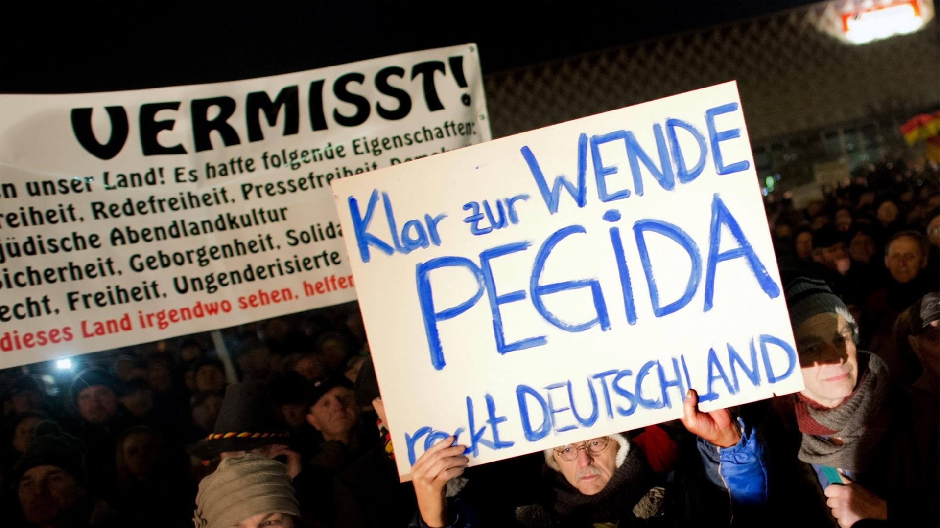 Teilnehmer einer Kundgebung der Pegida in Dresden (Sachsen) halten am 08.12.2014 Transparente in die Höhe. Teilnehmer einer Kundgebung der Pegida in Dresden (Sachsen) halten am 08.12.2014 Transparente in die Höhe.