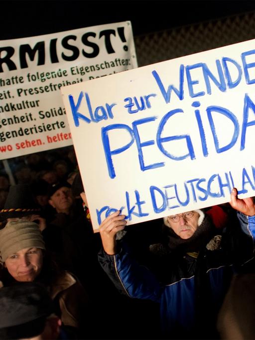 Teilnehmer einer Kundgebung der Pegida in Dresden (Sachsen) halten am 08.12.2014 Transparente in die Höhe.