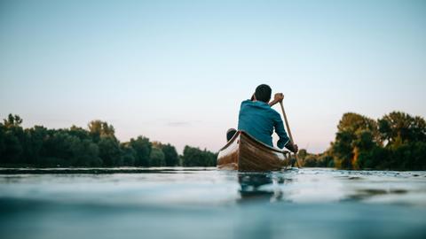 Blick auf einen See auf dem zwei Personen im Kanu fahren