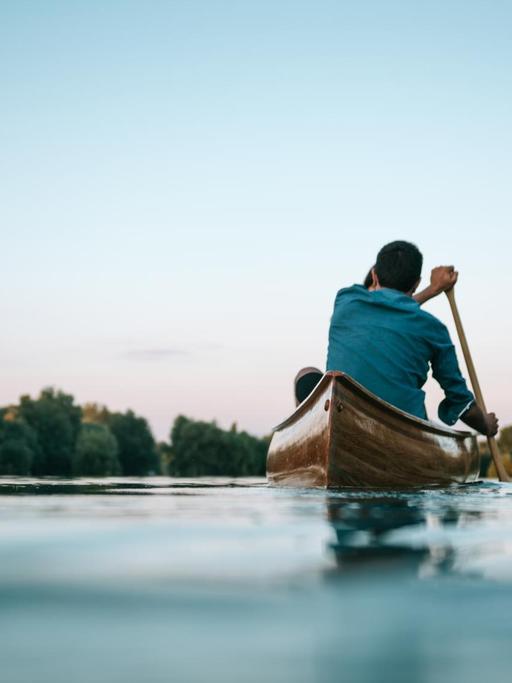 Blick auf einen See auf dem zwei Personen im Kanu fahren