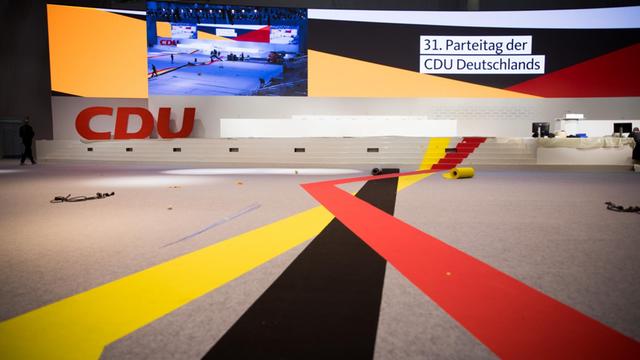 Schwarze, rote und gelbe Farbbahnen werden in der Messehalle für den 31. CDU-Parteitag ausgelegt.