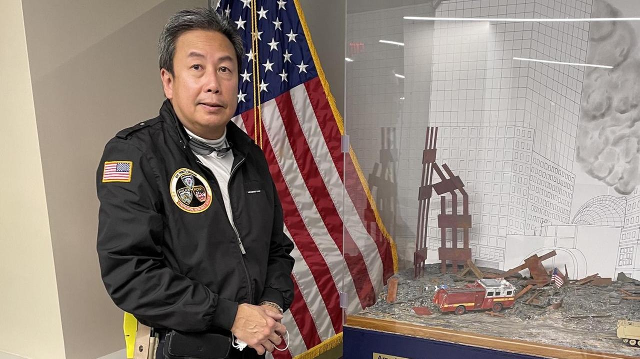 Der New Yorker Arzt Gordon Huie steht in einer schwarzen Uniform vor einer US-amerikanischen Flagge, neben ihm in einer Vitrine sind Gegenstände zu sehen, die an die Anschläge vom 11. September 2001 erinnern. Der New Yorker Arzt Gordon Huie steht in einer schwarzen Uniform vor einer US-amerikanischen Flagge, neben ihm in einer Vitrine sind Gegenstände zu sehen, die an die Anschläge vom 11. September 2001 erinnern.