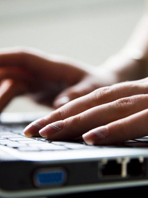 Lackierte Frauenhände tippen auf einerLaptoptastatur
