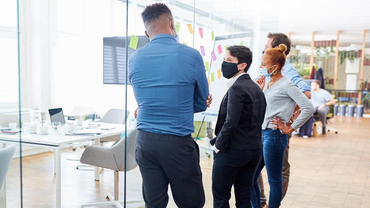 Kreativteam im Büro an einer Glaswand mit Zetteln Kreativteam im Büro an einer Glaswand mit Zetteln