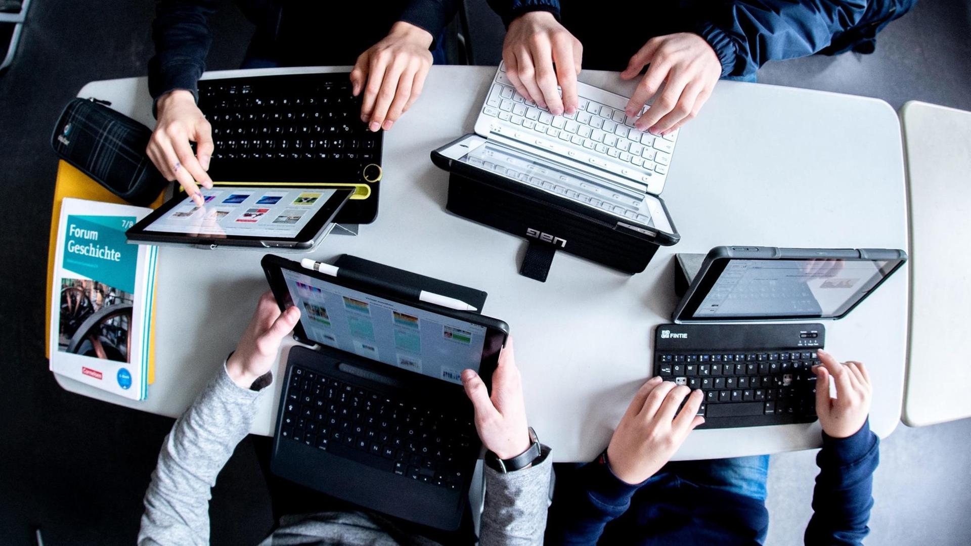 Aufsicht auf mehrere Schüler mit Laptops in den Händen. Aufsicht auf mehrere Schüler mit Laptops in den Händen.