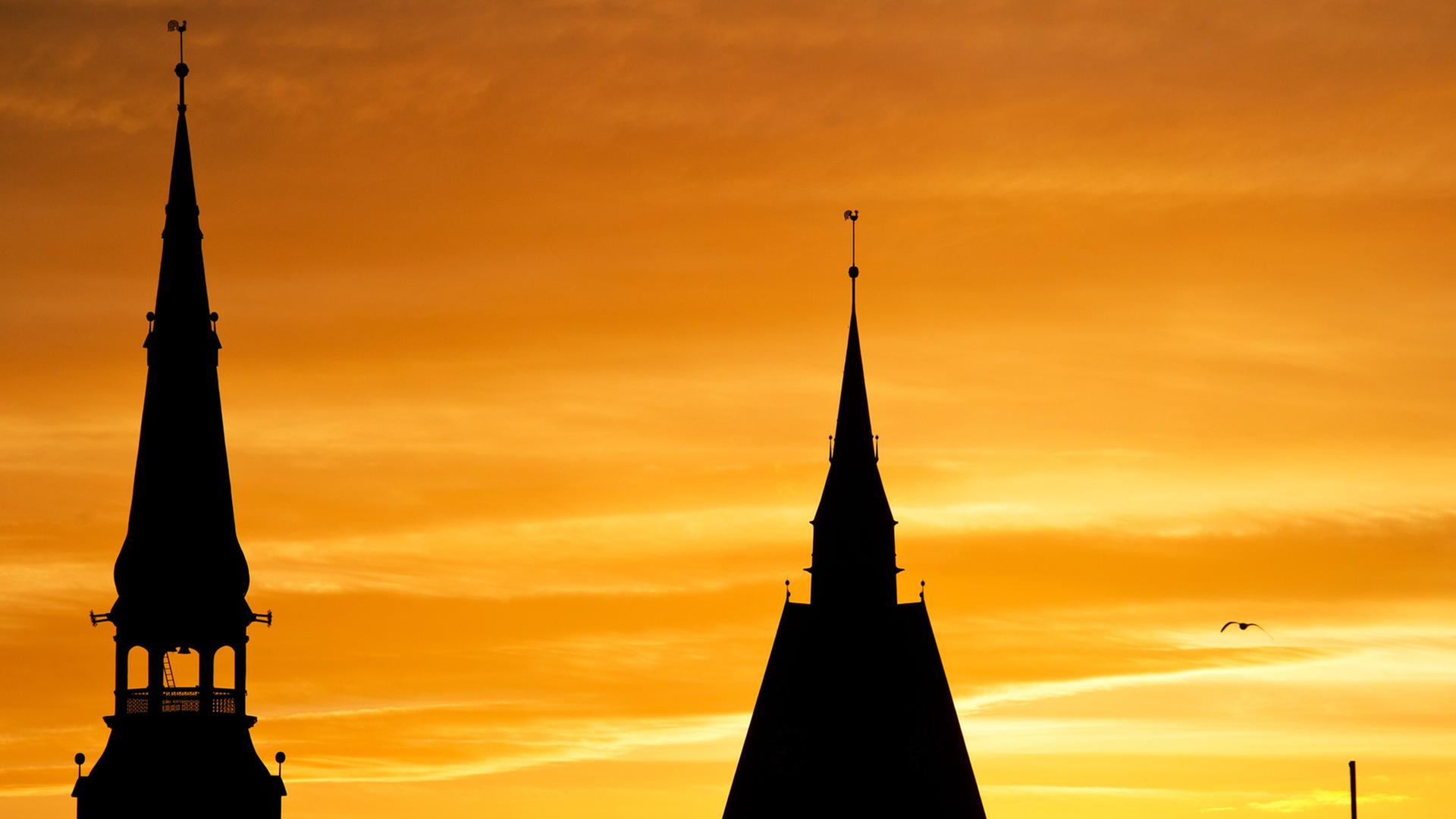 Die Kirchturmspitzen der Kreuzkirche (r) und der Marktkirche (l) sind am 07.01.2014 in Hannover bei Sonnenaufgang als schwarze Silhouetten zu sehen.