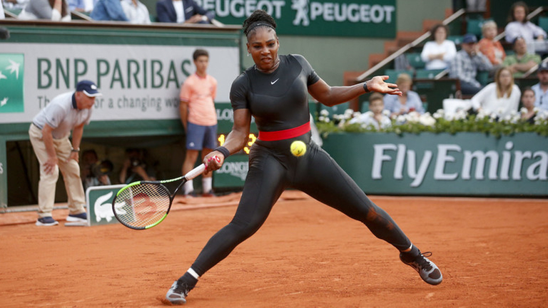 Die Tennis-Spielerin Serena Williams steht mit Tennis-Schläger auf dem Platz. Die Tennis-Spielerin Serena Williams steht mit Tennis-Schläger auf dem Platz.