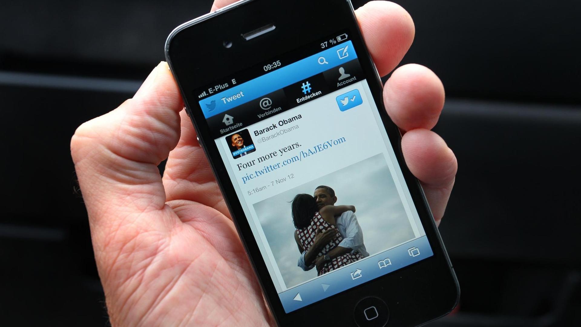 Smartphone auf dessen Display die Twitter-Nachricht "Four more years" von Barack Obama angezeigt wird.