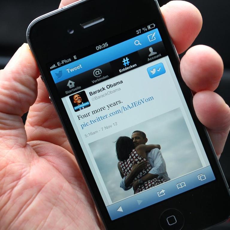 Smartphone auf dessen Display die Twitter-Nachricht "Four more years" von Barack Obama angezeigt wird. 