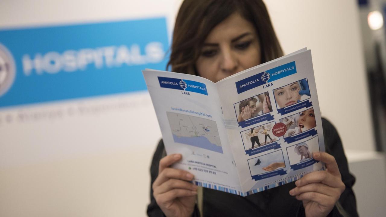 A hostess poses with information material for a hospital in Turkey at a section for medical tourism at the International Tourism Trade Fair (ITB) on March 8, 2017 in Berlin. / AFP PHOTO / STEFFI LOOS