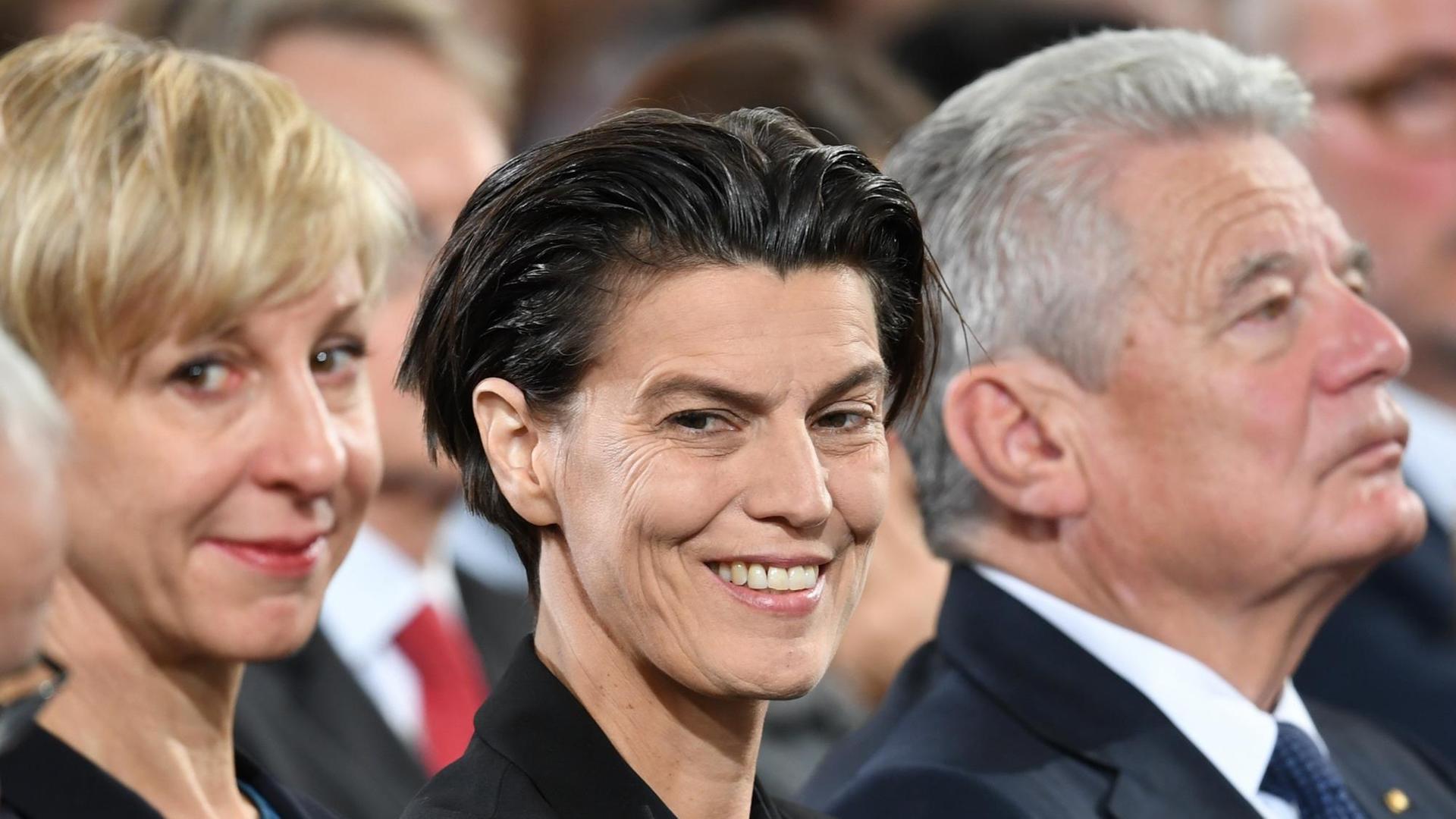 Die Publizistin Carolin Emcke sitzt zwischen ihrer Lebensgefährtin Silvia Fehrmann und Bundespräsident Joachim Gauck und lächelt. Die Publizistin Carolin Emcke sitzt zwischen ihrer Lebensgefährtin Silvia Fehrmann und Bundespräsident Joachim Gauck und lächelt.