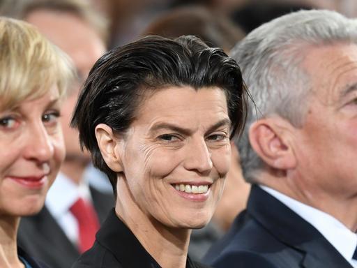 Die Publizistin Carolin Emcke sitzt zwischen ihrer Lebensgefährtin Silvia Fehrmann und Bundespräsident Joachim Gauck und lächelt.