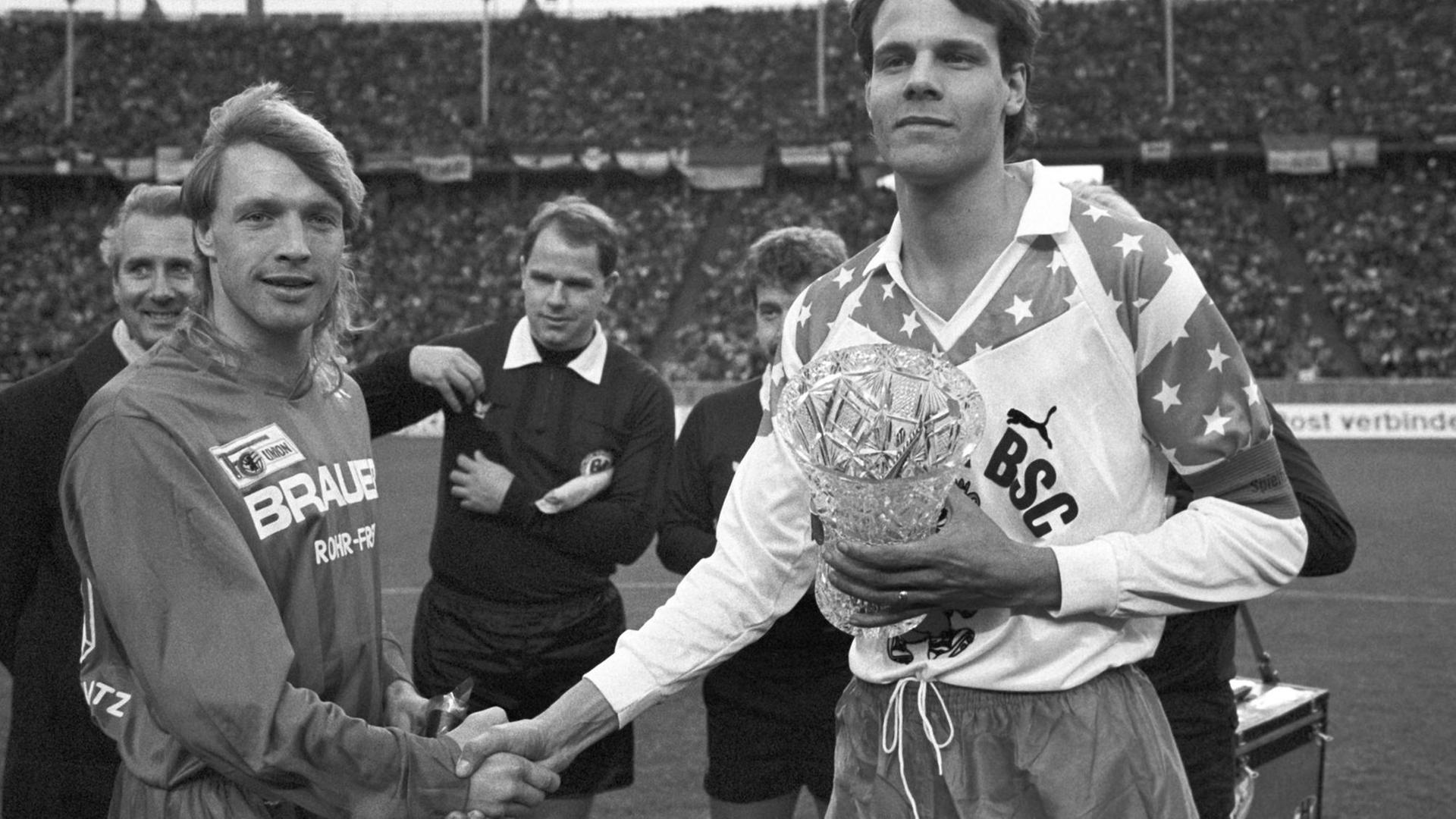 Die beiden Mannschaftskapitäne geben sich vor Beginn des innerstädtischen "Fußball-Gipfels" zwischen Hertha BSC und Union Berlin am 27.01.1990 im Olympiastadion in Berlin die Hand. Die beiden Mannschaftskapitäne geben sich vor Beginn des innerstädtischen "Fußball-Gipfels" zwischen Hertha BSC und Union Berlin am 27.01.1990 im Olympiastadion in Berlin die Hand.