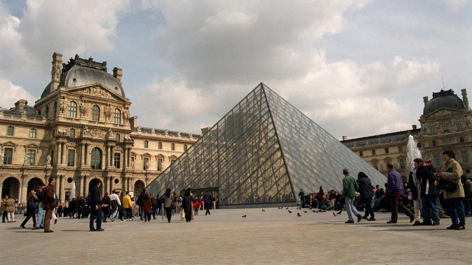 Touristen warten vor der gläsernen Pyramide im Hof des Louvres Touristen warten vor der gläsernen Pyramide im Hof des Louvres