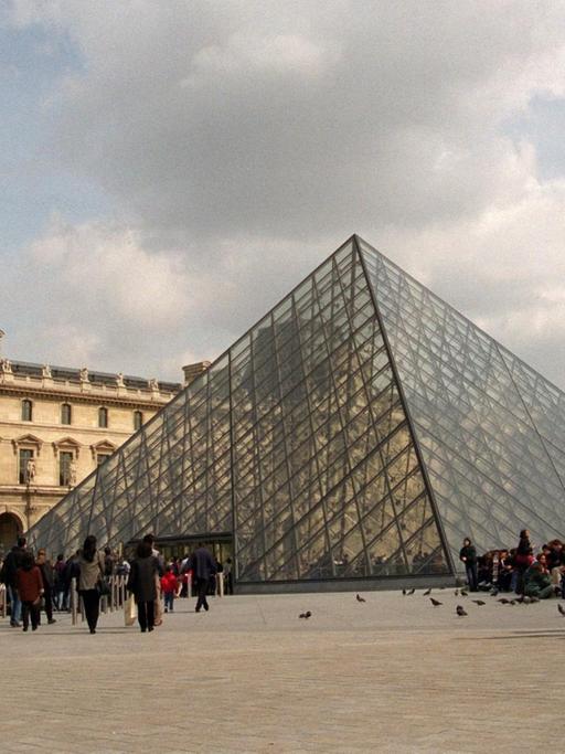 Touristen warten vor der gläsernen Pyramide im Hof des Louvres