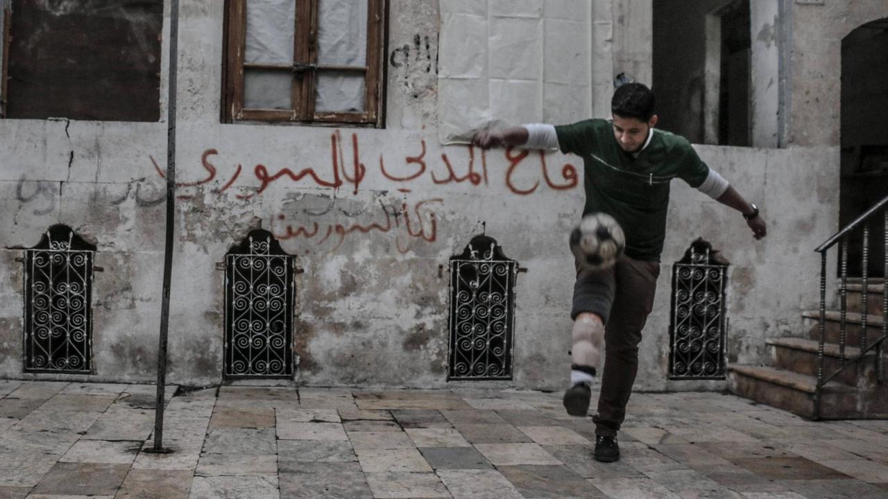 Eine Straßenszene zeigt einen jungen Mann beim Fußball spielen in einem von Rebellen kontrollierten Gebiet in Aleppo 2015. Der Spieler verlor ein Bein nach einem Bombenangriff von Truppen des syrischen Präsidenten Bashar al-Assad. Eine Straßenszene zeigt einen jungen Mann beim Fußball spielen in einem von Rebellen kontrollierten Gebiet in Aleppo 2015. Der Spieler verlor ein Bein nach einem Bombenangriff von Truppen des syrischen Präsidenten Bashar al-Assad.