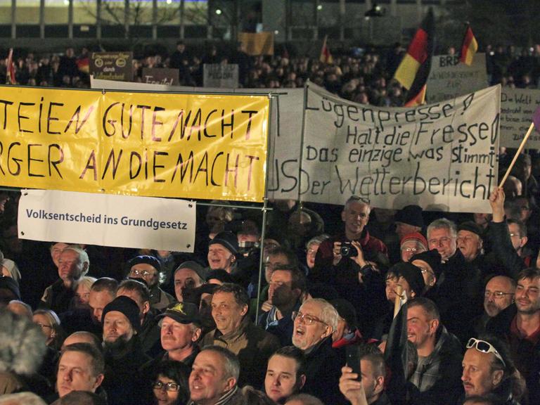 Pegida-Demonstranten in Dresden halten am 15. Dezember 2014 Banner hoch.