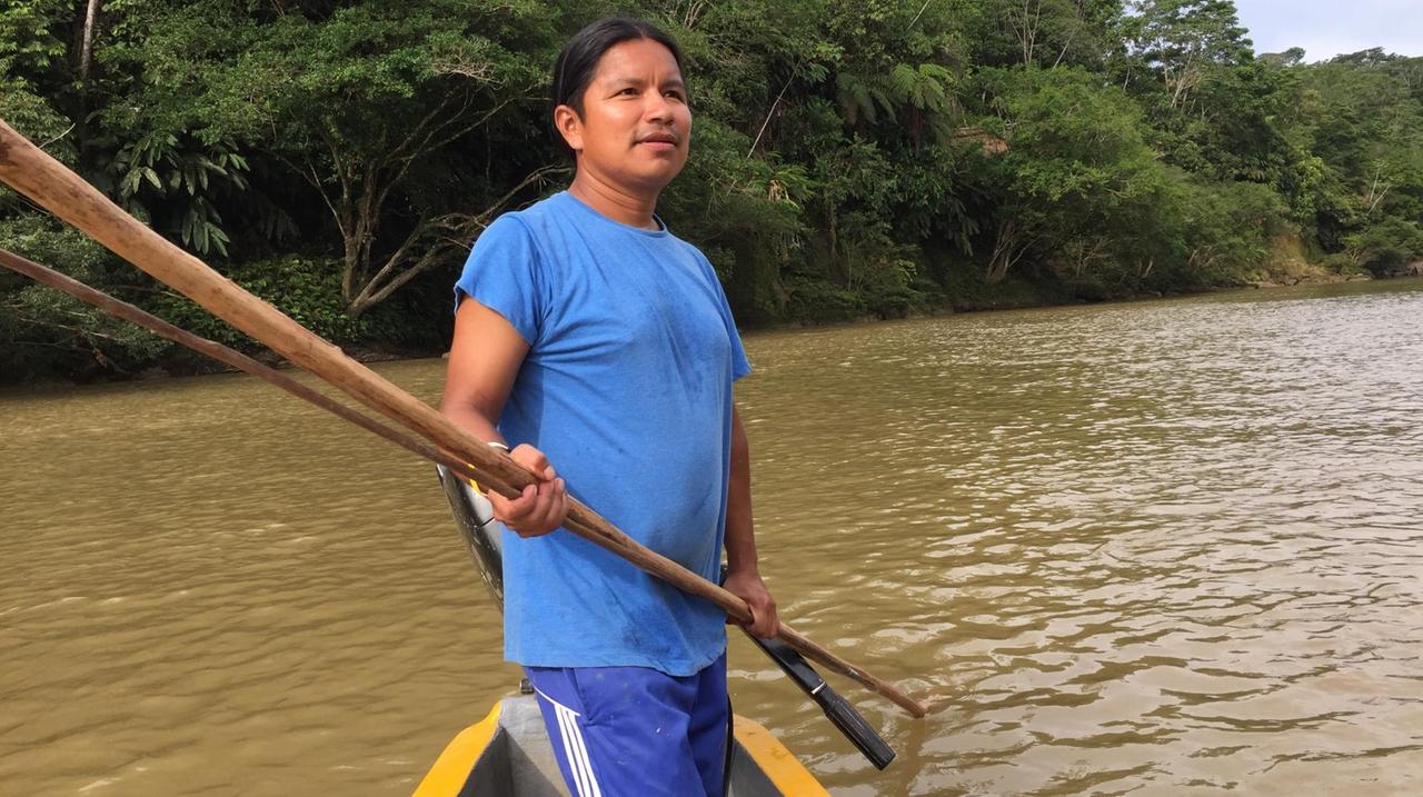 Ein Fischer steht in seinem Boot auf dem braunen Amazonas.