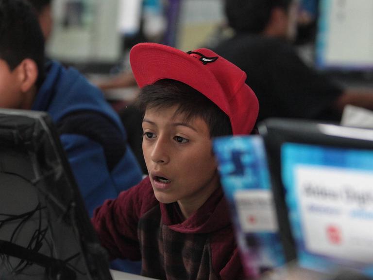 Ein Junge sitzt erstaunt vor einem Computerbildschirm.