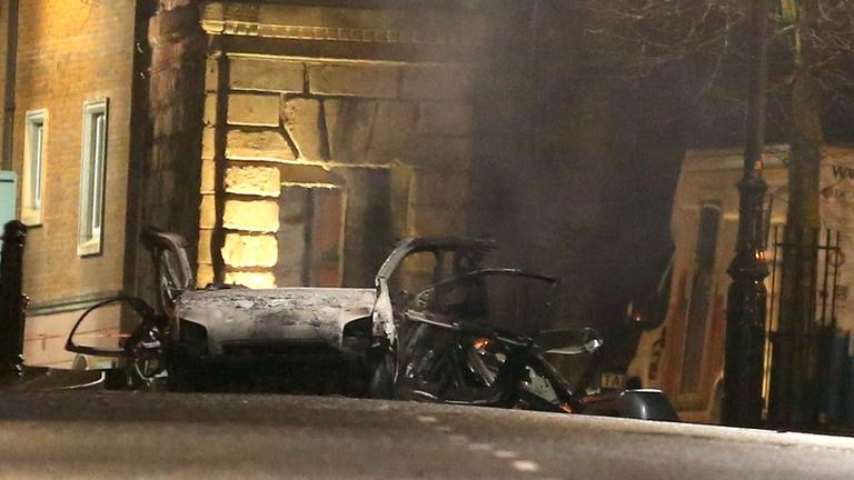 Ein zerstörtes Auto steht im Dunkeln am Explosionsort auf der Bishop Street. Ein zerstörtes Auto steht im Dunkeln am Explosionsort auf der Bishop Street.
