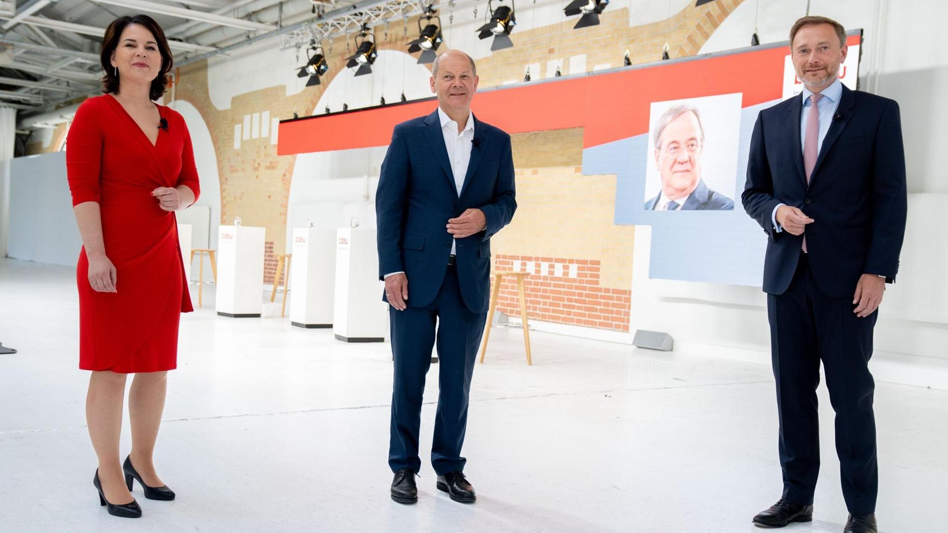 Annalena Baerbock (l), Kanzlerkandidatin und Bundesvorsitzende von Bündnis 90/Die Grünen, Olaf Scholz, SPD-Kanzlerkandidat und Bundesminister der Finanzen, und Christian Lindner, FDP-Spitzenkandidat, Fraktionsvorsitzender und Parteivorsitzender der FDP, stehen zu Beginn einer Gesprächsrunde zusammen in einem Studio. Im Hintergrund ist eine Digitalbild von Armin Laschet (CDU), CDU-Kanzlerkandidat und Ministerpräsident von Nordrhein-Westfalen, zu sehen. Annalena Baerbock (l), Kanzlerkandidatin und Bundesvorsitzende von Bündnis 90/Die Grünen, Olaf Scholz, SPD-Kanzlerkandidat und Bundesminister der Finanzen, und Christian Lindner, FDP-Spitzenkandidat, Fraktionsvorsitzender und Parteivorsitzender der FDP, stehen zu Beginn einer Gesprächsrunde zusammen in einem Studio. Im Hintergrund ist eine Digitalbild von Armin Laschet (CDU), CDU-Kanzlerkandidat und Ministerpräsident von Nordrhein-Westfalen, zu sehen.