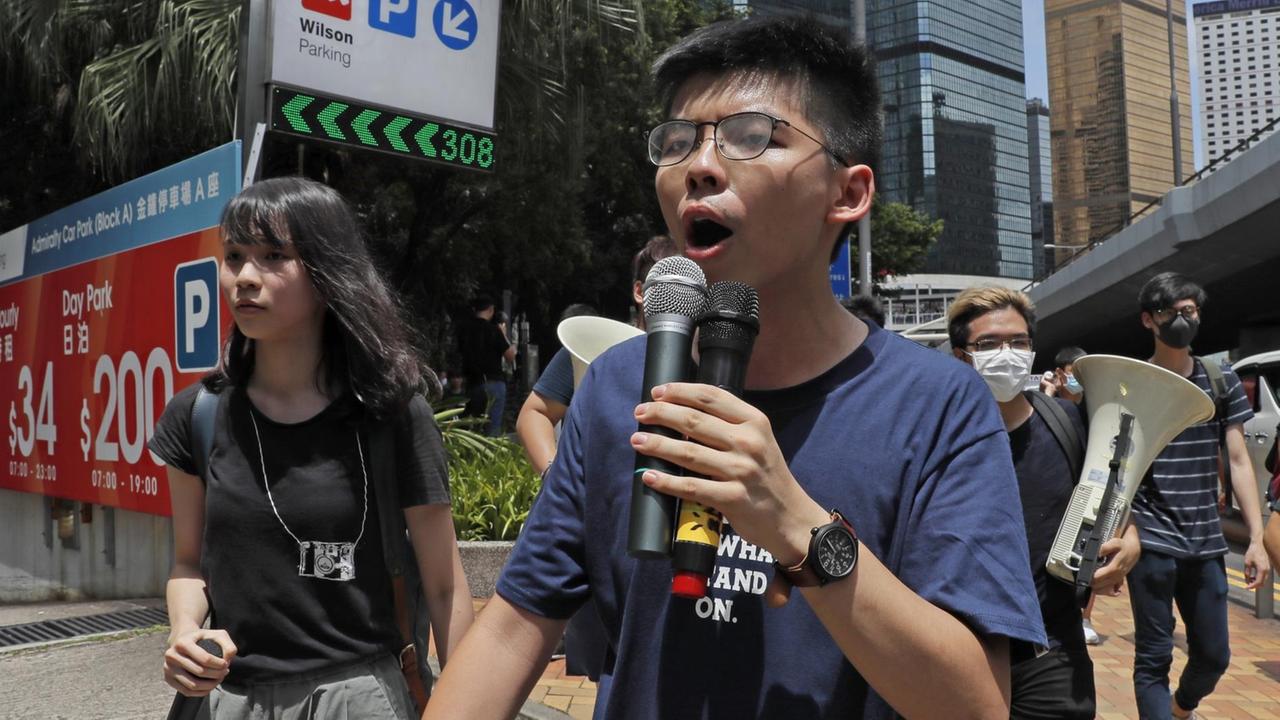 Der Demokratie-Aktivist Joshua Wong und seine Mitstreiterin Agnes Chow bei einer Demonstration in Hongkong, im Sommer 2019, auf einer Straße. (AP Photo/Kin Cheung) Der Demokratie-Aktivist Joshua Wong und seine Mitstreiterin Agnes Chow bei einer Demonstration in Hongkong, im Sommer 2019, auf einer Straße. (AP Photo/Kin Cheung)