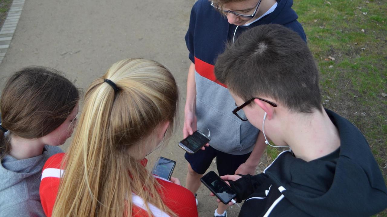 Schülerinnen und Schüler in einem Halbkreis mit ihren Smartphones. Schülerinnen und Schüler in einem Halbkreis mit ihren Smartphones.