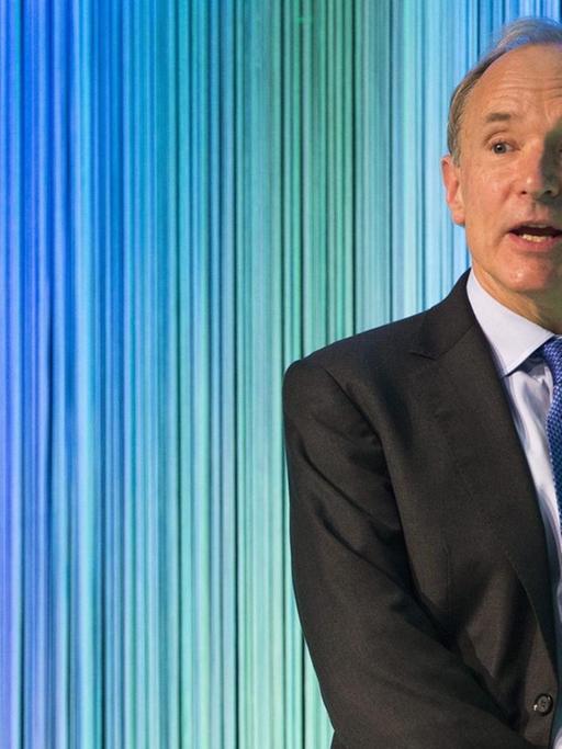 Tim Berners-Lee spricht beom Gottlieb Duttweiler Preis in Zürich in der Schweitz. Im Hintergrund blau-grüne Linien.