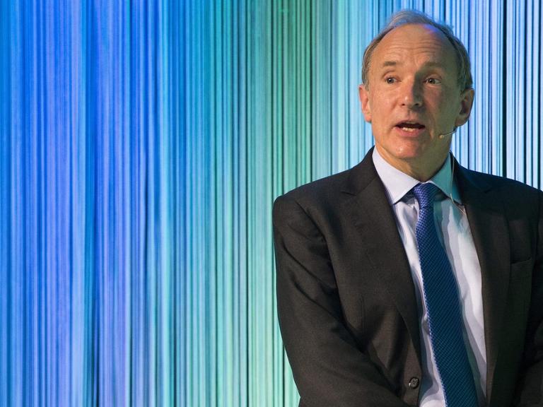 Tim Berners-Lee spricht beom Gottlieb Duttweiler Preis in Zürich in der Schweitz. Im Hintergrund blau-grüne Linien.