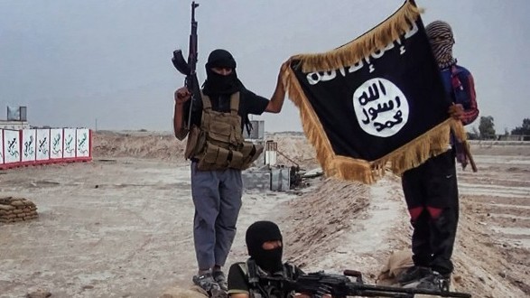 IS-Kämpfer mit Maschinengewehren posieren mit der schwarzen Flagge der Gruppe für ein Foto