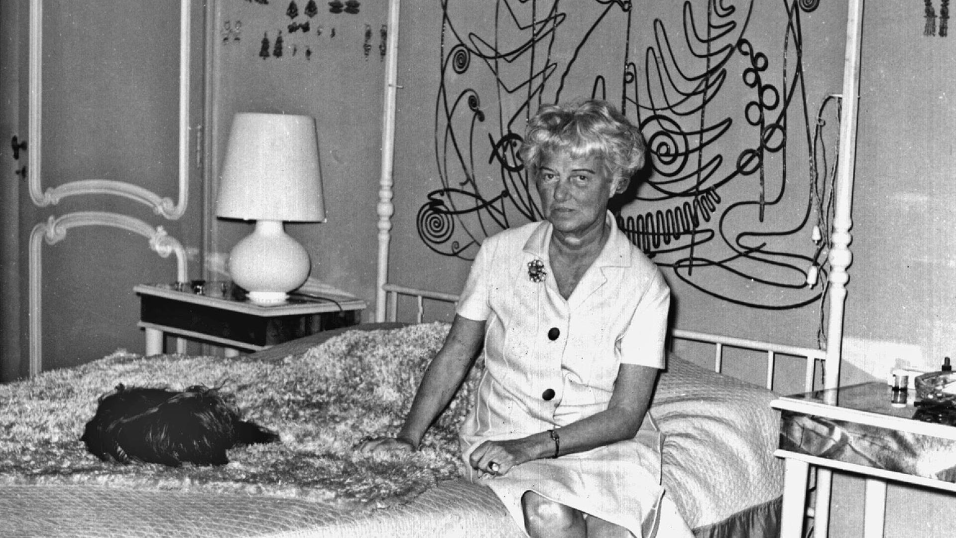 Die US-amerikanische Kunstmäzenin und -sammlerin Peggy Guggenheim sitzt auf einem Himmelbett im Schlafzimmer ihres Hauses in Venedig; undatierte Aufnahme.
