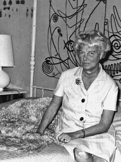 Die US-amerikanische Kunstmäzenin und -sammlerin Peggy Guggenheim sitzt auf einem Himmelbett im Schlafzimmer ihres Hauses in Venedig; undatierte Aufnahme.