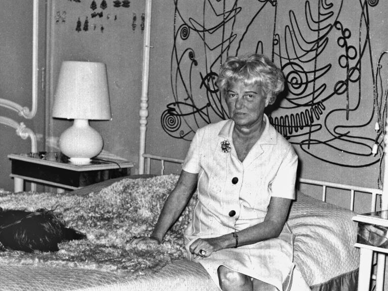 Die US-amerikanische Kunstmäzenin und -sammlerin Peggy Guggenheim sitzt auf einem Himmelbett im Schlafzimmer ihres Hauses in Venedig; undatierte Aufnahme.