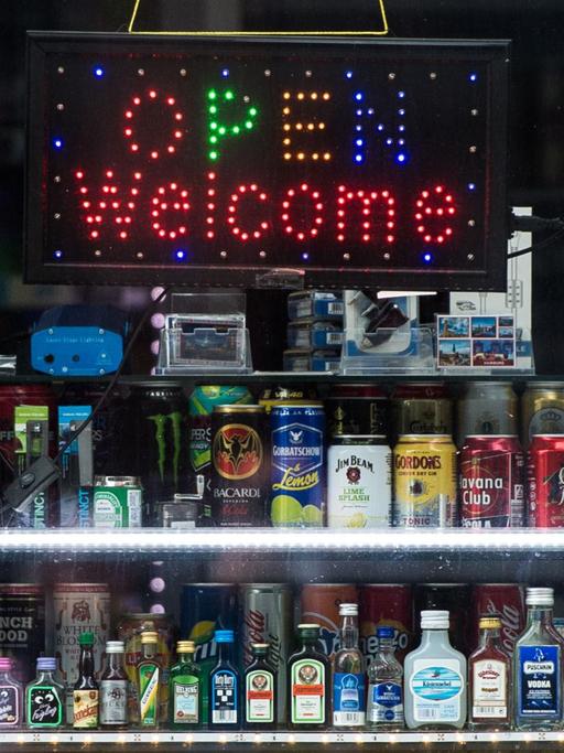 Eine Leuchttafel mit dem Schriftzug "Open Welcome" und zahlreiche alkoholische Getränke stehen am 23.05.2016 in Hamburg in dem Fenster von einem Kiosk.