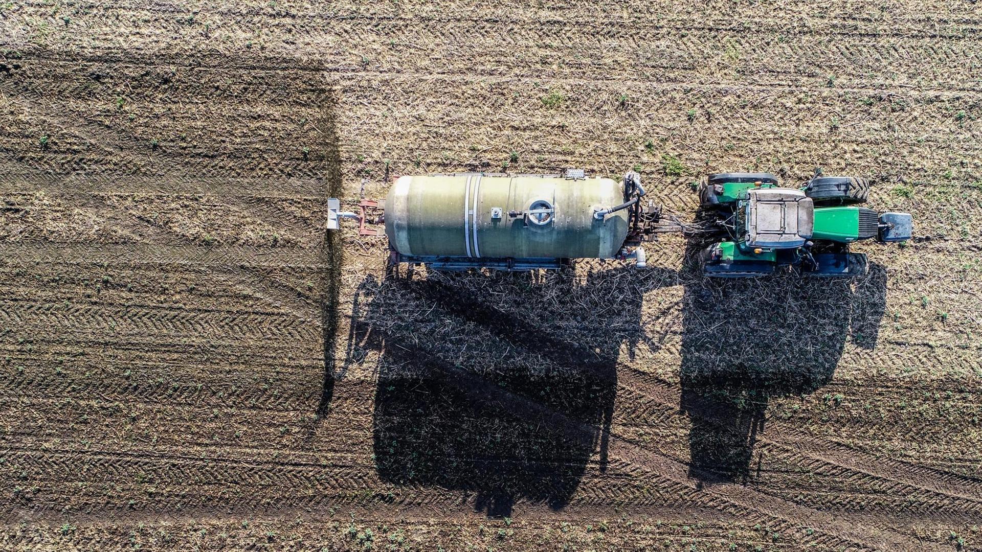 Ein Trecker düngt ein Feld mit Gärresten aus einer Biogasanlage Ein Trecker düngt ein Feld mit Gärresten aus einer Biogasanlage