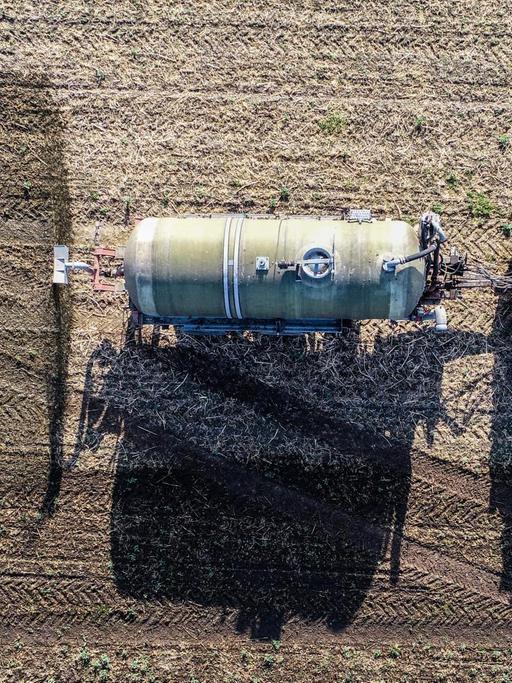 Ein Trecker düngt ein Feld mit Gärresten aus einer Biogasanlage