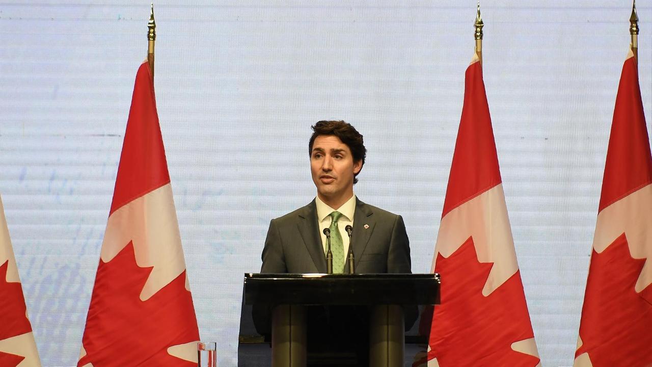 Kanadas Premierminister Justin Trudeau steht an einem Rednerpult, hinter ihm kanadische Flaggen.