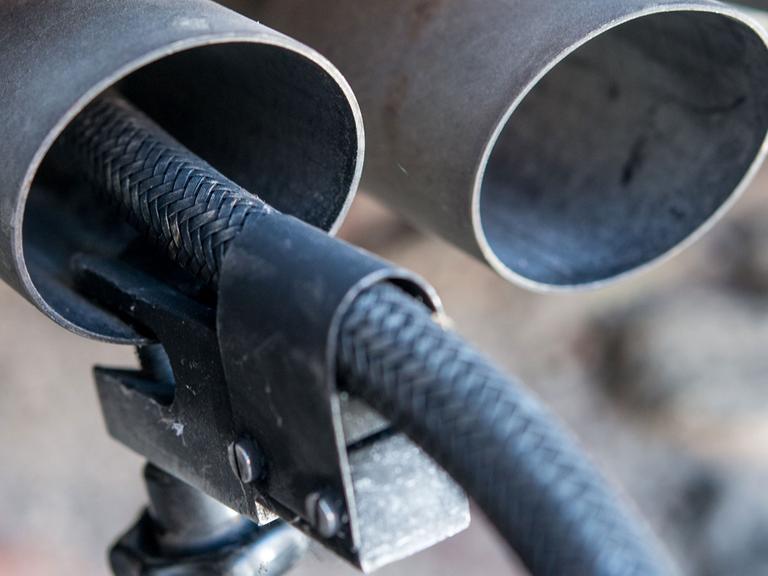 Ein Messschlauch eines Gerätes zur Abgasuntersuchung für Dieselmotoren steckt im Auspuffrohr eines VW-Autos.