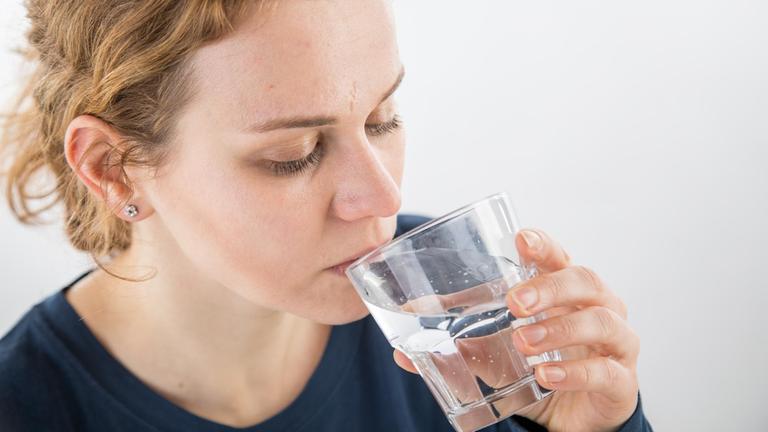 Eine Frau trinkt einen Schluck Wasser (gestellte Szene)