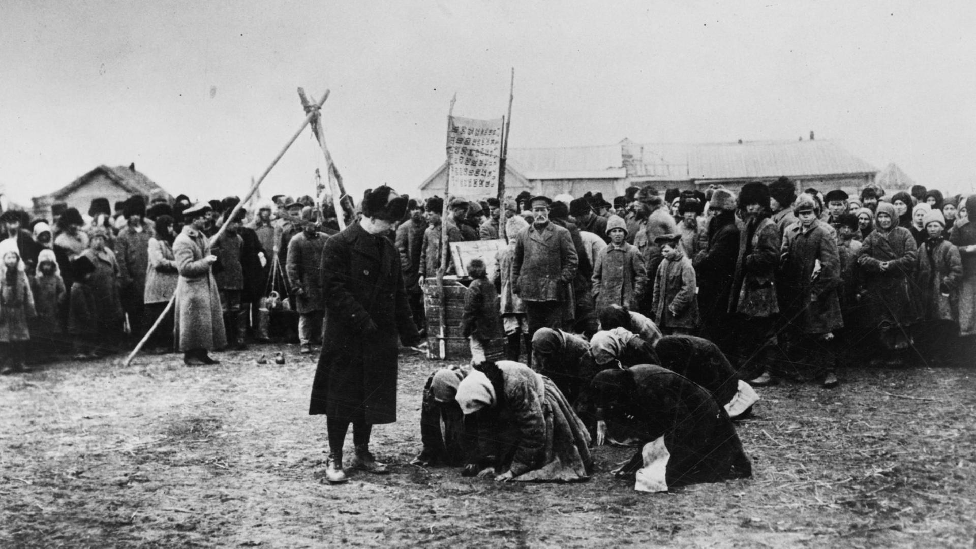 Mutmaßlich hungernde russische Frauen knien vor einem Mann, vermutlich Offizier der Hilfsorganisation American Relief Administration Mutmaßlich hungernde russische Frauen knien vor einem Mann, vermutlich Offizier der Hilfsorganisation American Relief Administration