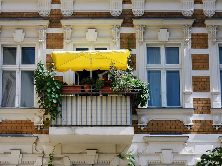 Ein bepflanzter Balkon mit einem gelben Sonnenschirm, fotografiert am 06.07.2017 in Berlin Mitte.