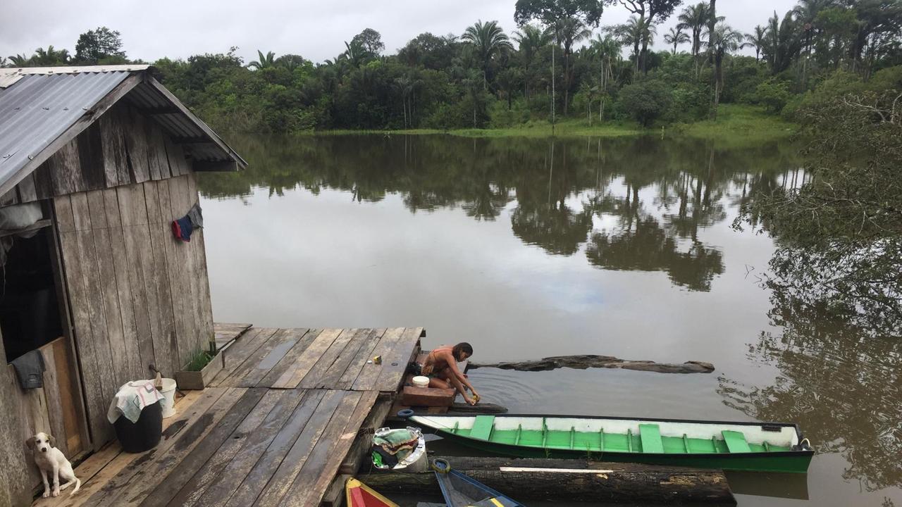 Bunte Boote liegen im Wasser, daneben ein Holzhaus. Bunte Boote liegen im Wasser, daneben ein Holzhaus.